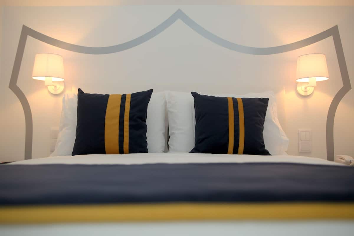 A hotel room with a bed, two bedside lamps, and a modern headboard.