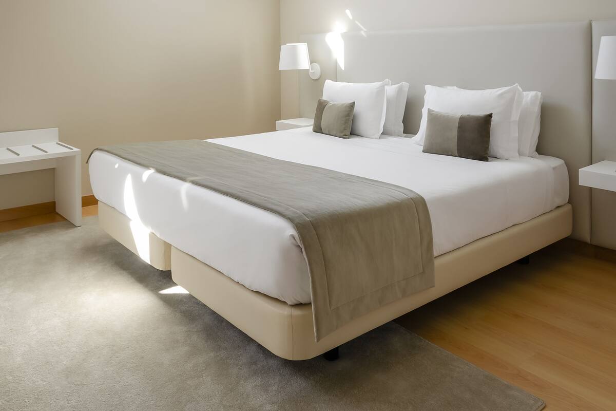 A modern bedroom with a large bed, bedside tables, and a skylight.
