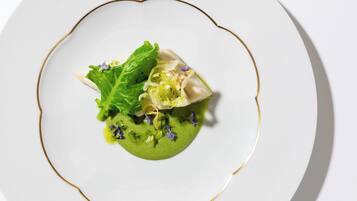 A white plate with a green sauce, a leaf, and a piece of food.