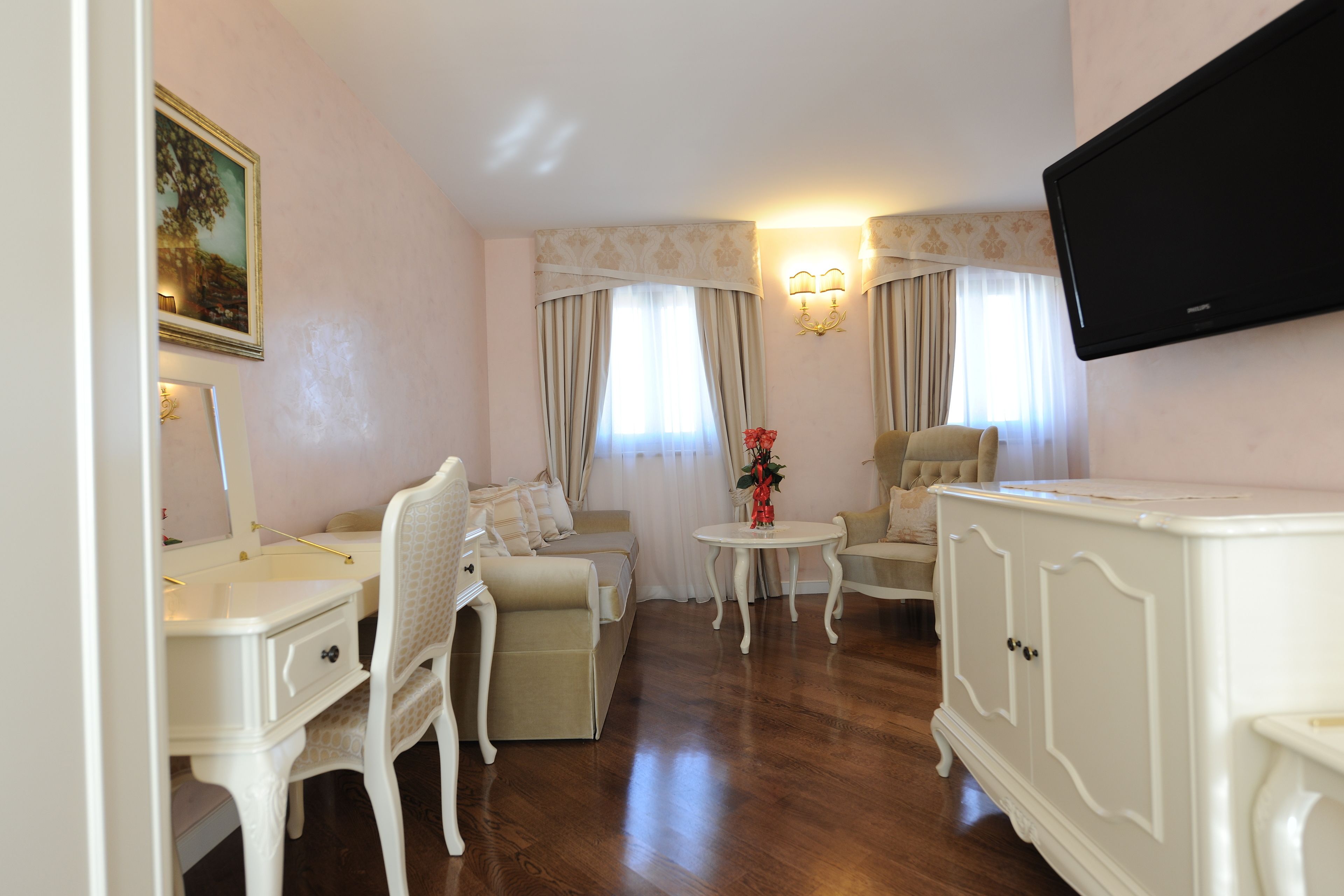Une pièce comprenant un canapé, deux fauteuils, une petite table, un meuble et un téléviseur fixé au mur.
