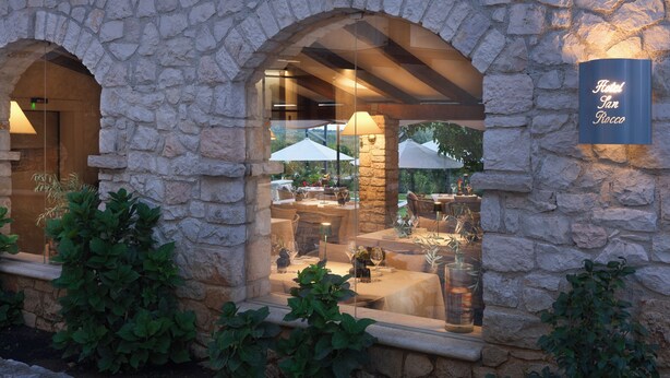 A stone building with arched windows, a sign reading 'Hotel San Rocco,' and outdoor seating with umbrellas. - Heritage Hotel San Rocco (Brtonigla)