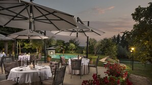 An outdoor dining area with tables and chairs, umbrellas, and a pool in the background. - Heritage Hotel San Rocco (Brtonigla)