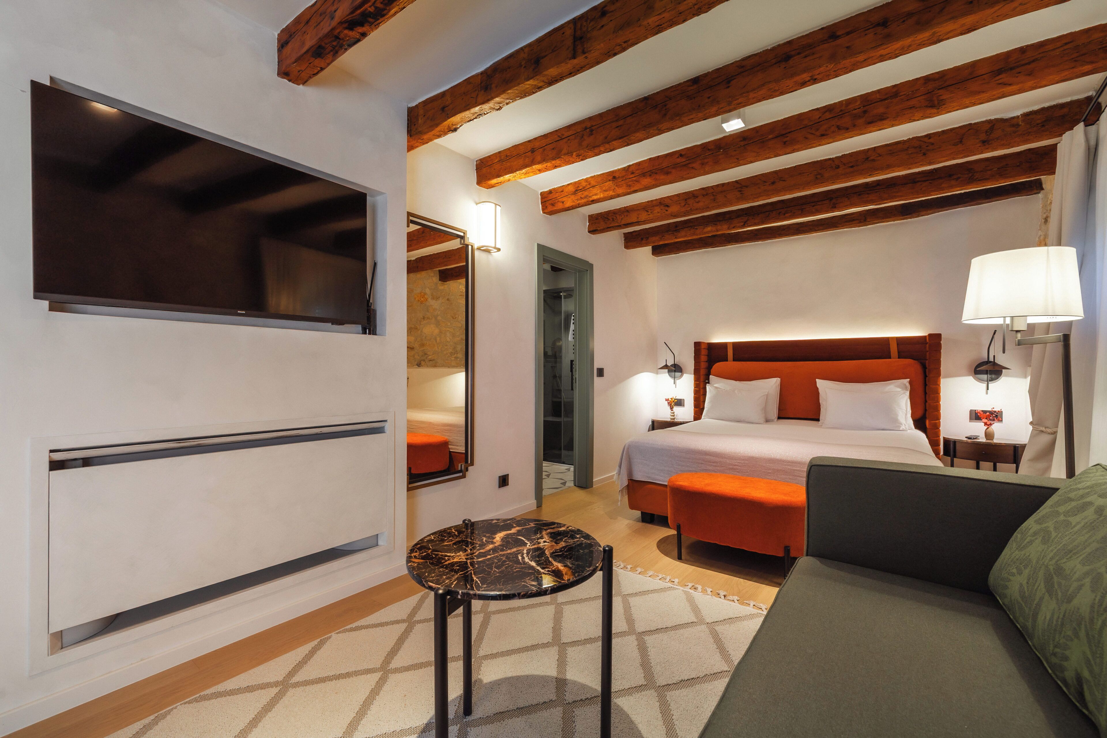 Een moderne hotelkamer met een groot bed, een bank, een kleine tafel en een televisie.
