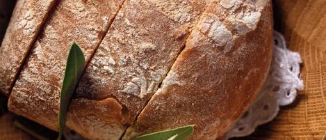 A loaf of bread in a wooden bowl with a lace doily underneath.