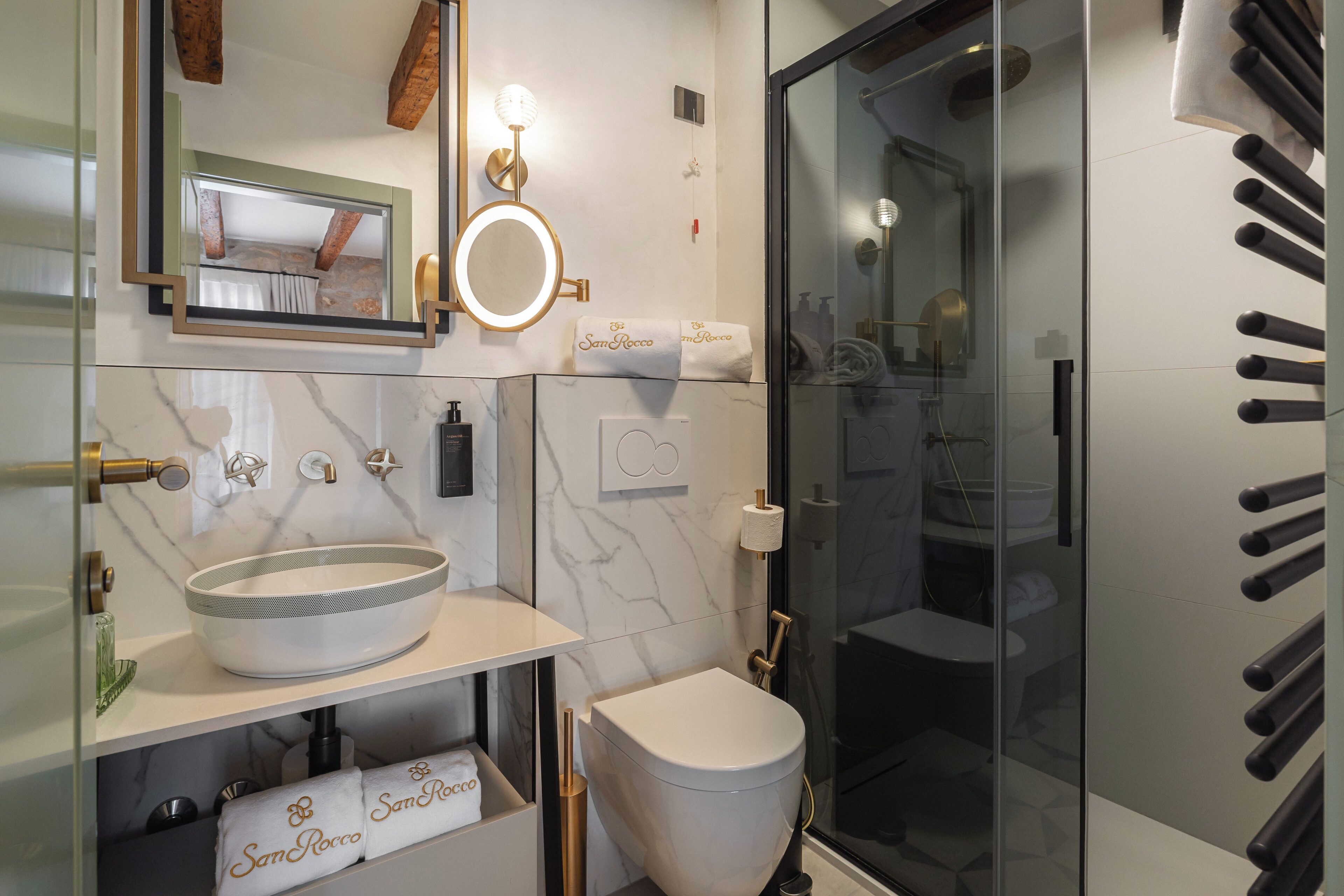 A modern bathroom with a glass shower enclosure, a marble sink, and a toilet.