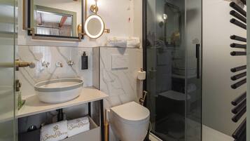 A modern bathroom with a glass shower enclosure, a marble sink, and a toilet.