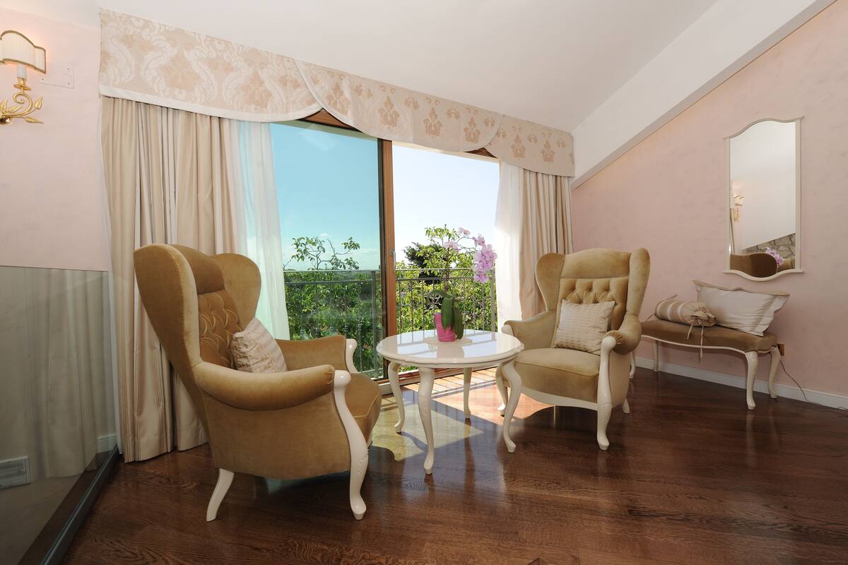 A room with two armchairs, a small round table, and a mirror on the wall.