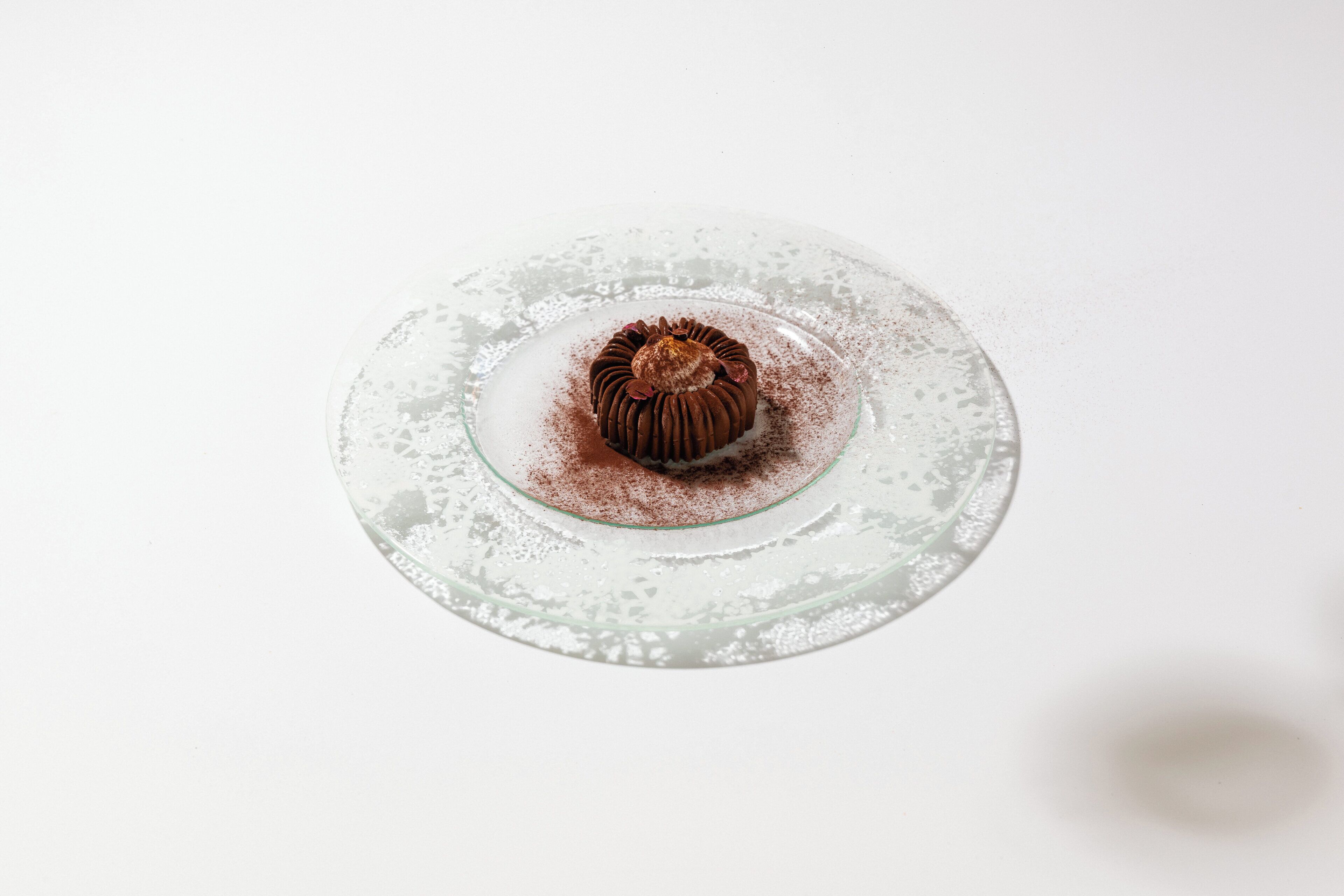 A dessert on a glass plate with a dusting of cocoa powder.
