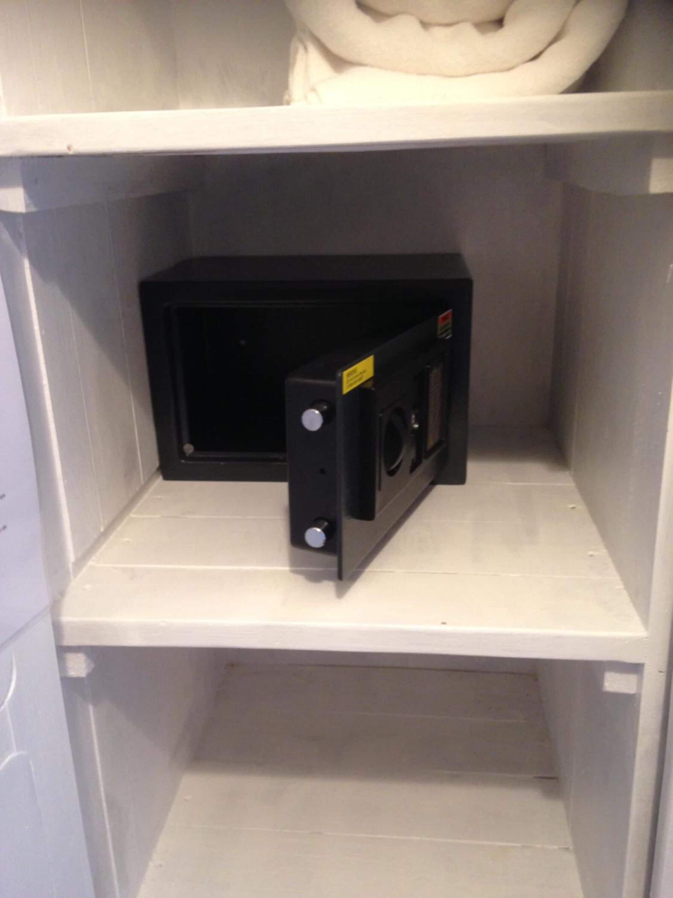 Un microondas negro sobre un estante blanco en una cocina.