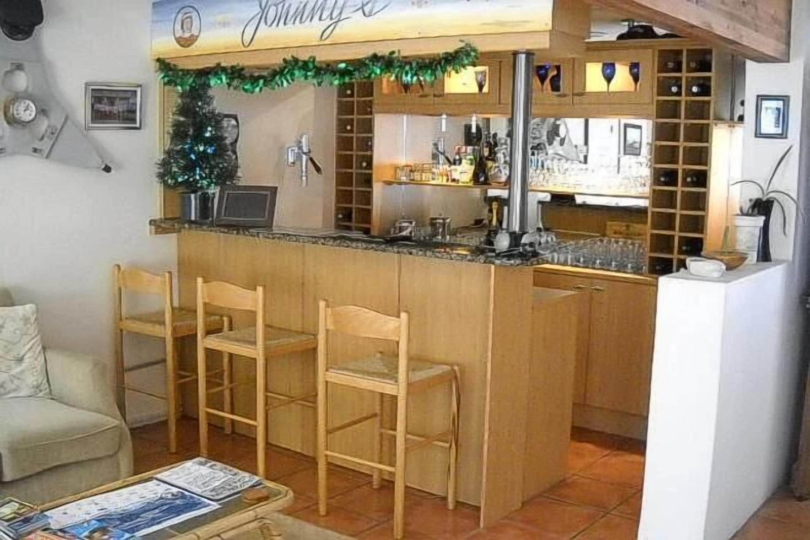 Une cuisine compacte avec un coin bar, des chaises en bois et une petite table à manger.