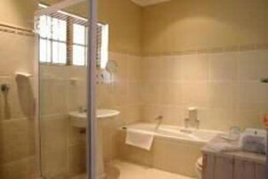 A bathroom with a glass shower enclosure, a bathtub, and a sink.