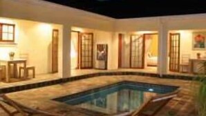 Zona junto a la piscina con piscina rectangular, un área de estar cubierta y una zona de comedor.
