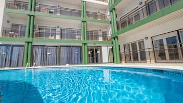Una piscina al aire libre de temporada, sombrillas, tumbonas