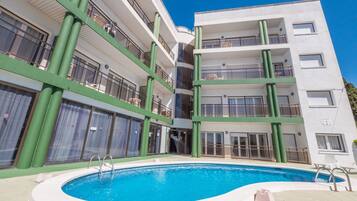 Una piscina al aire libre de temporada, sombrillas