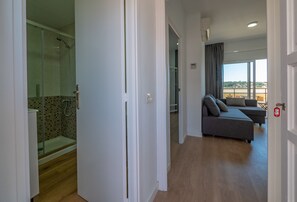 Une chambre d’hôtel moderne dotée d’une douche, d’un canapé et d’un balcon avec vue.