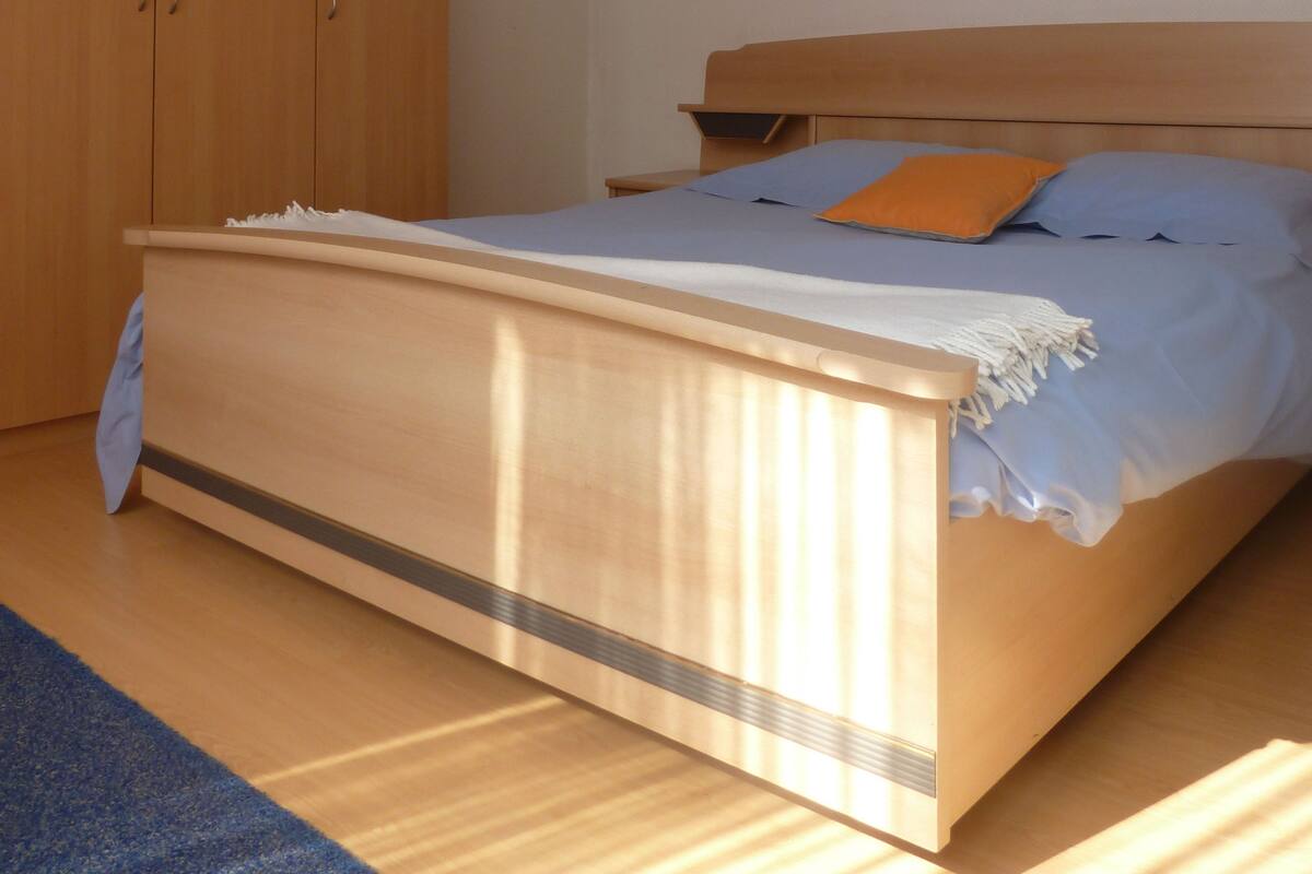 Une chambre à coucher avec un lit en bois, une table de chevet et une armoire.