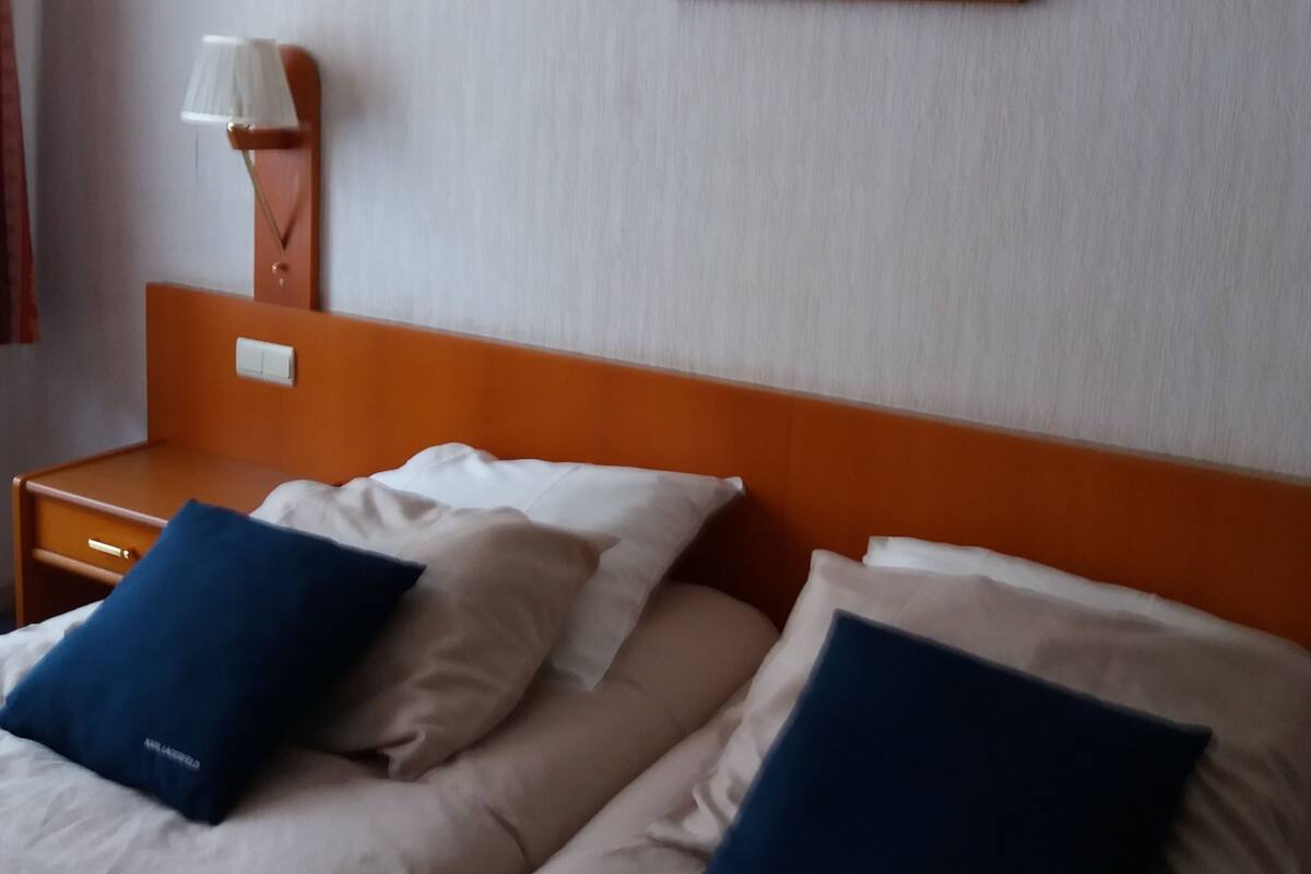 Une chambre d’hôtel avec deux lits, une table de chevet avec une lampe et un tableau au mur.