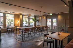 A restaurant with a central bar, multiple seating areas, and large windows offering views of the street. - Het Hart van Weesp (Weesp)