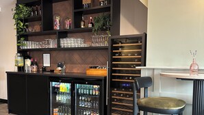 A bar area with shelves stocked with bottles, glasses, and a wine cooler. - Het Hart van Weesp (Weesp)
