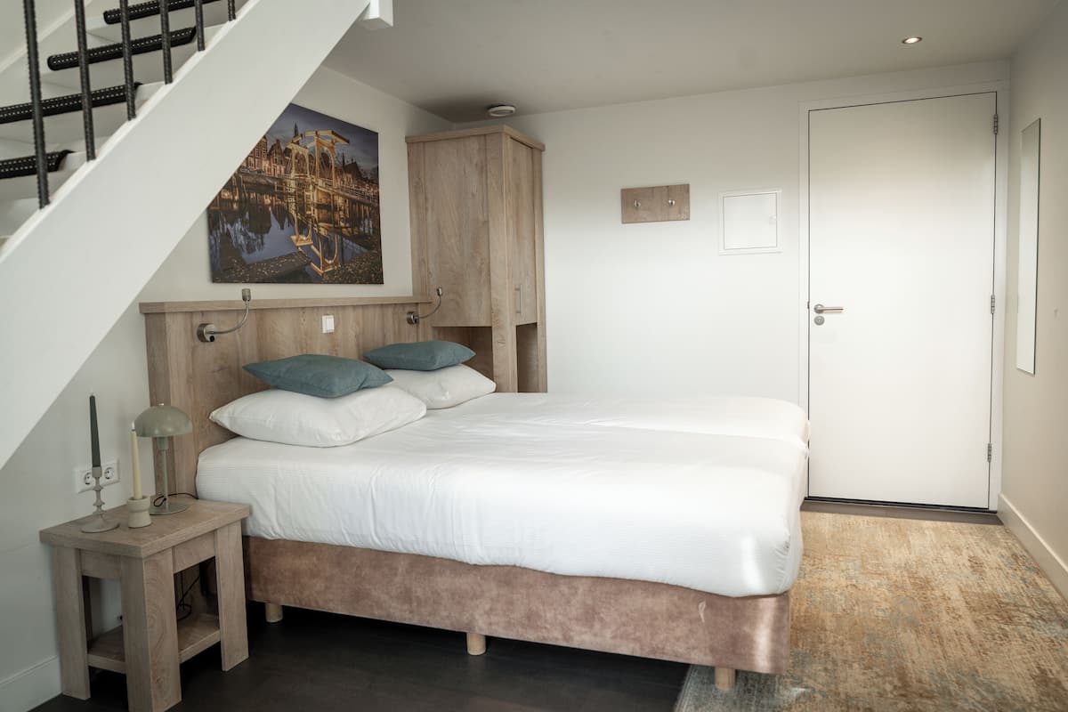 A bedroom with a bed, a nightstand, a wooden cabinet, a painting, and a door.
