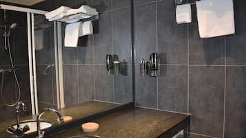 Enjoy a refreshing shower with a handheld showerhead and unwind in a spacious bathroom with a large mirror and sink.