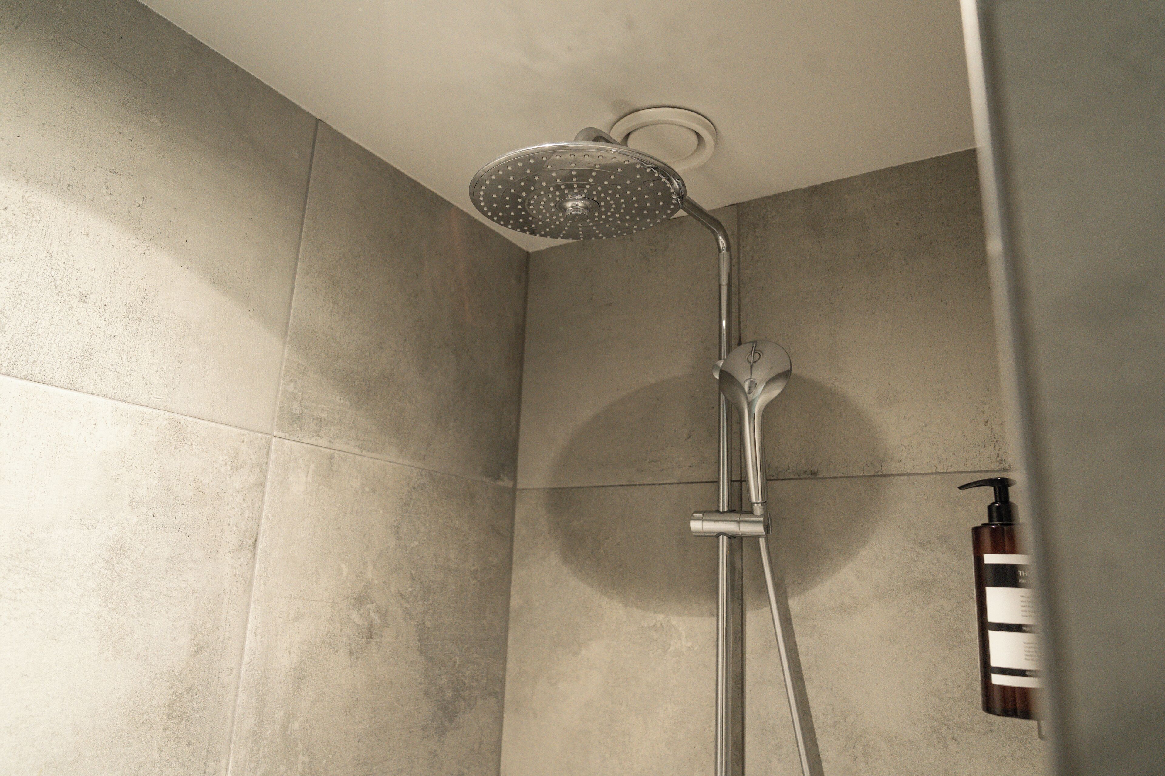 A shower with a handheld showerhead and a handheld faucet.