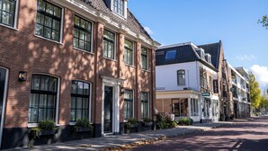 A row of traditional European-style buildings with brick facades, large windows, and a clear sky. - Het Hart van Weesp (Weesp)