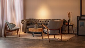 A living room with a sofa, two chairs, a coffee table, a vase with dried plants, and a modern stove. - Het Hart van Weesp (Weesp)
