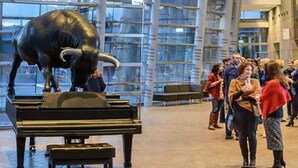 A spacious lobby with a large glass wall, a grand piano, and a sculpture of a bull.
