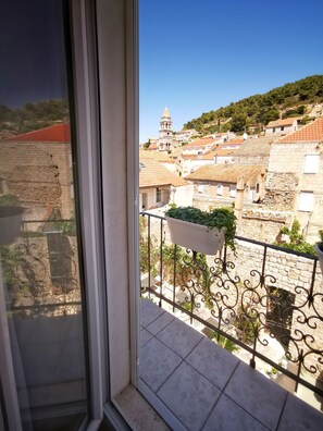 A balcony with a view of a historic town, including a tower and terracotta-roofed buildings.
