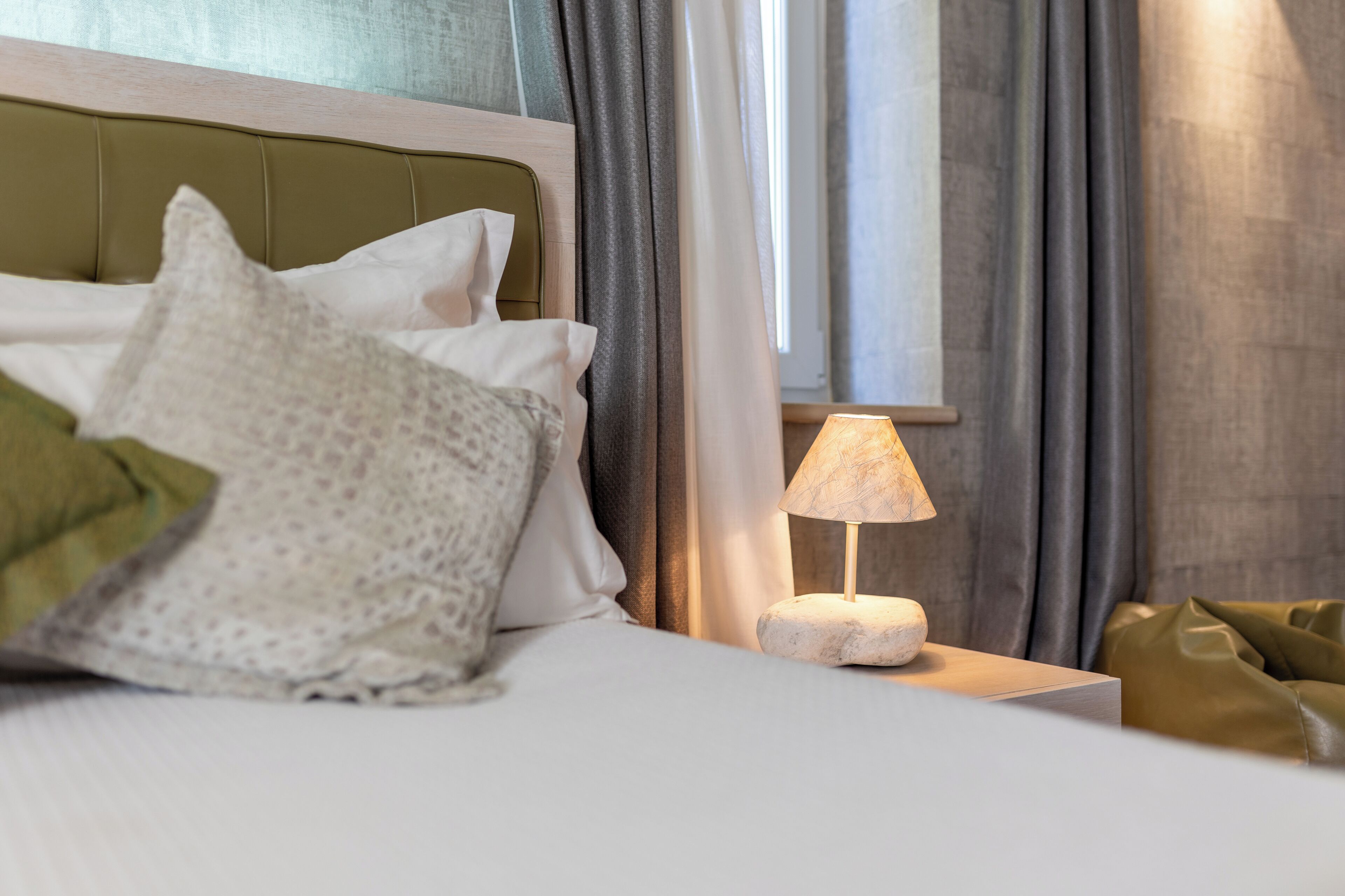 A neatly made bed with pillows and a bedside lamp in a hotel room.