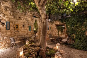 Un espace extérieur aménagé avec des murs en pierre, un arbre et des lanternes.