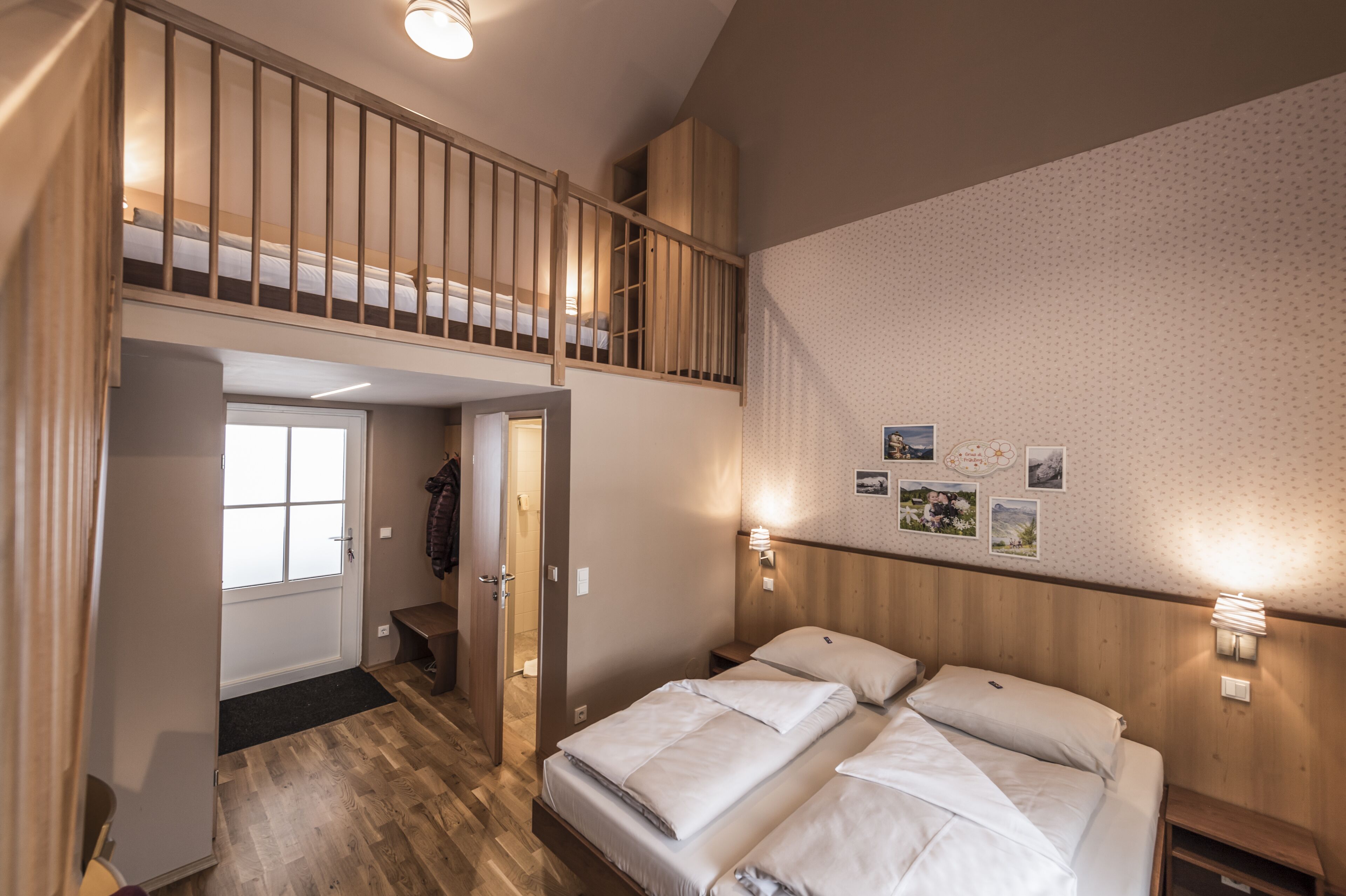 A bedroom with a bunk bed, a wooden ceiling, and a wall with framed pictures.