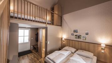 A bedroom with a bunk bed, a wooden ceiling, and a wall with framed pictures.