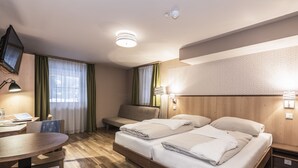 Een hotelkamer met een bed, een bureau, een stoel, een televisie en een lamp.