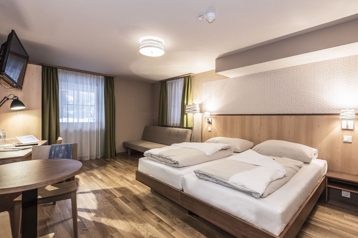 Una habitación de hotel con cama, escritorio, silla, televisor y lámpara.