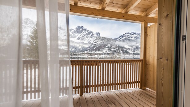 Een houten terras met uitzicht op besneeuwde bergen.