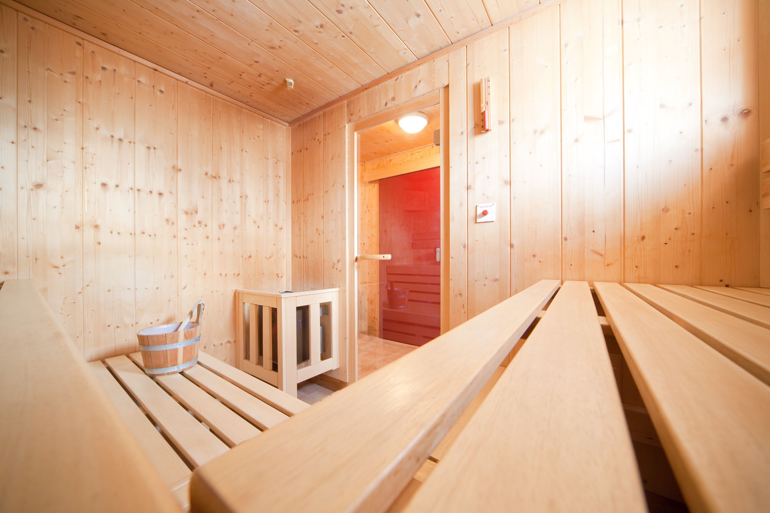 A wooden sauna room with benches and a small cabinet.