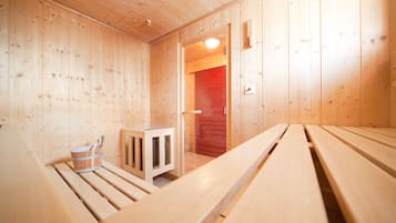 A wooden sauna room with benches and a small cabinet.
