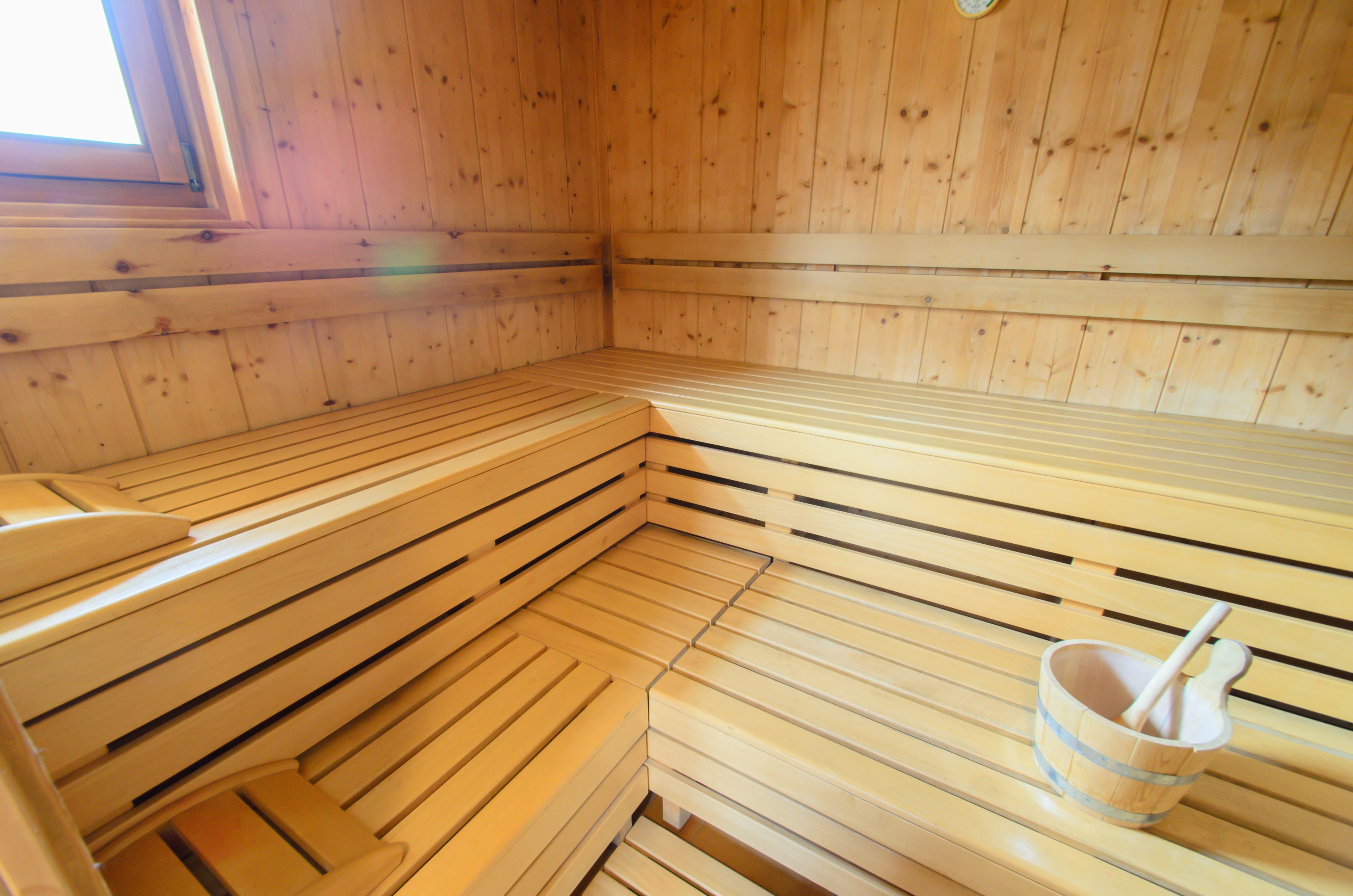 A sauna with wooden benches and a wooden bucket with a brush.