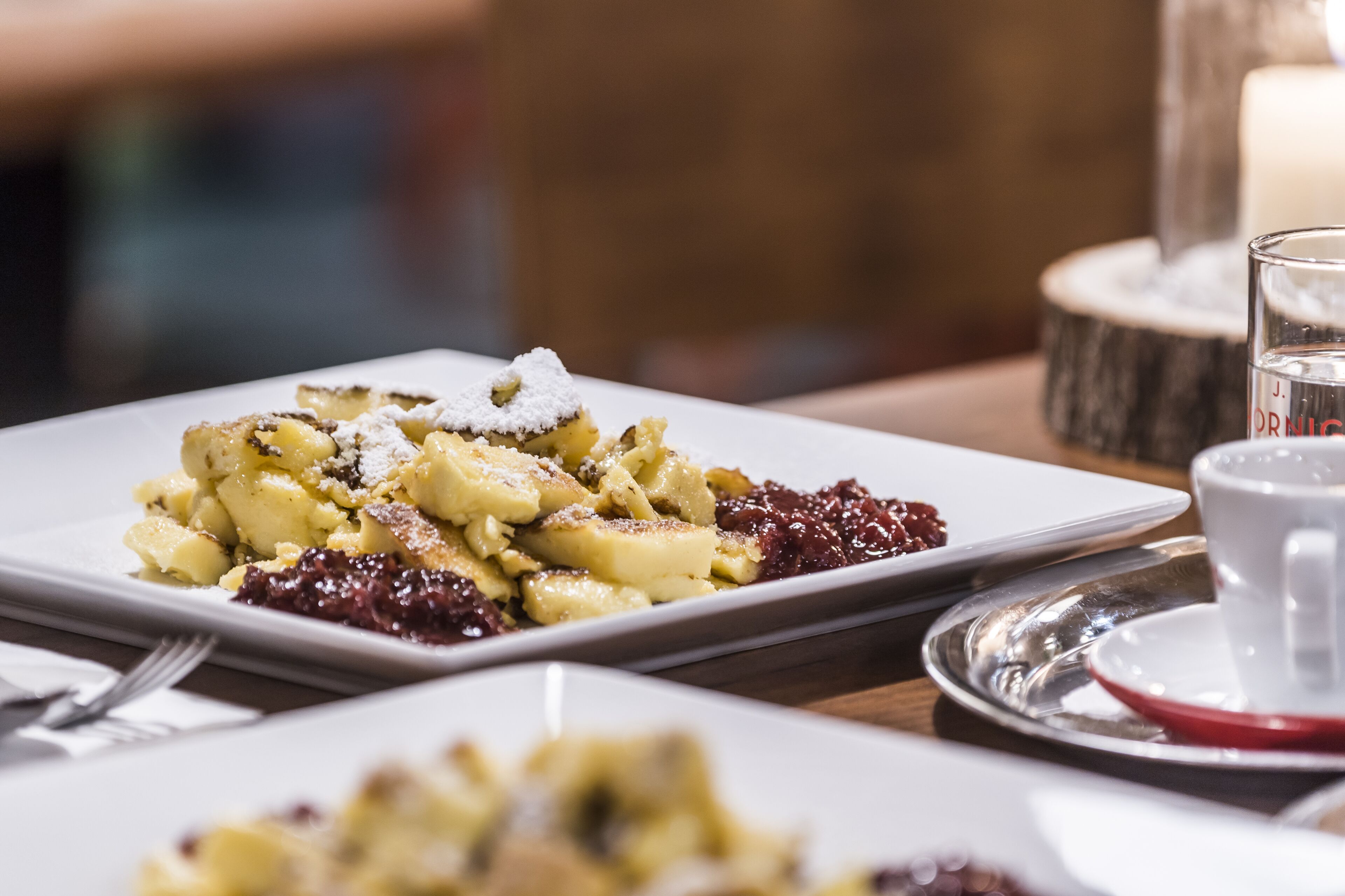 Un piatto di dessert con zucchero a velo e un bicchiere d'acqua su un tavolo.