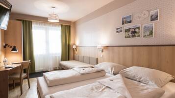 A hotel room with two beds, a desk, and a chair. There are wall-mounted lamps and a ceiling light.