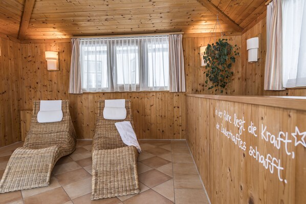 A wooden room with two wicker recliners, a window with sheer curtains, and a wall with text.