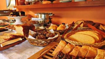 Een buffet met diverse broden, gebak en een pot met de tekst 'Pão de Alecrim'.