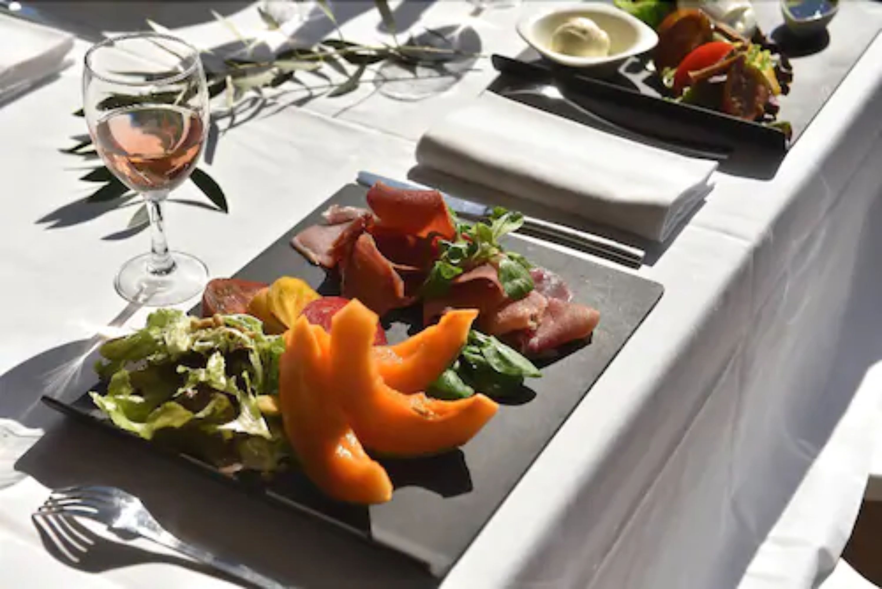Une table dressée avec des assiettes remplies de nourriture, un verre de vin et des couverts.