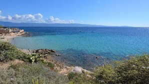Küstliche Ansicht mit klarem, blauem Wasser, felsiger Küstenlinie und entfernten Bergen.