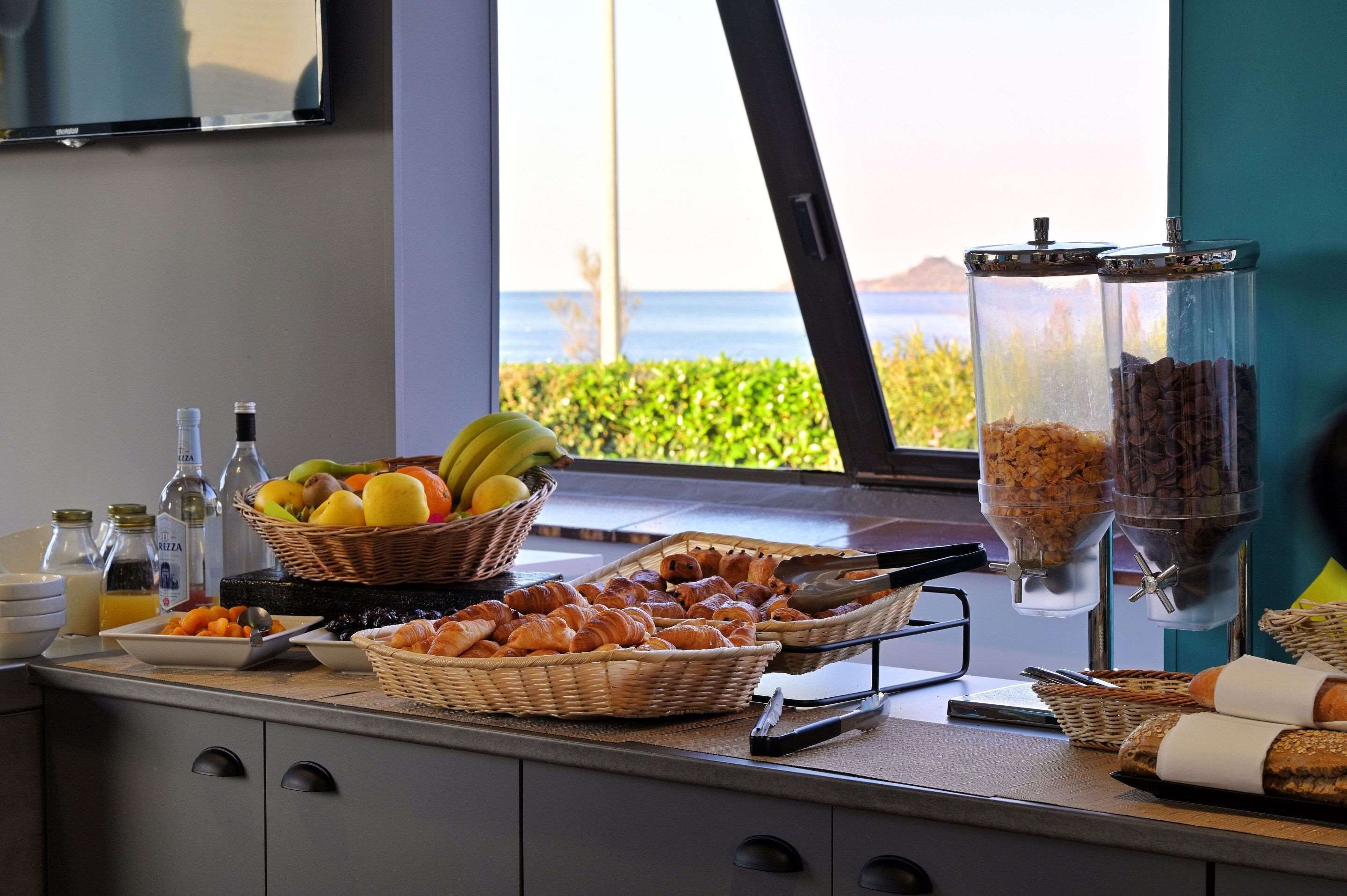 A breakfast buffet with fruits, pastries, and coffee dispensers.
