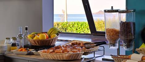 A breakfast buffet with fruits, pastries, and coffee dispensers.