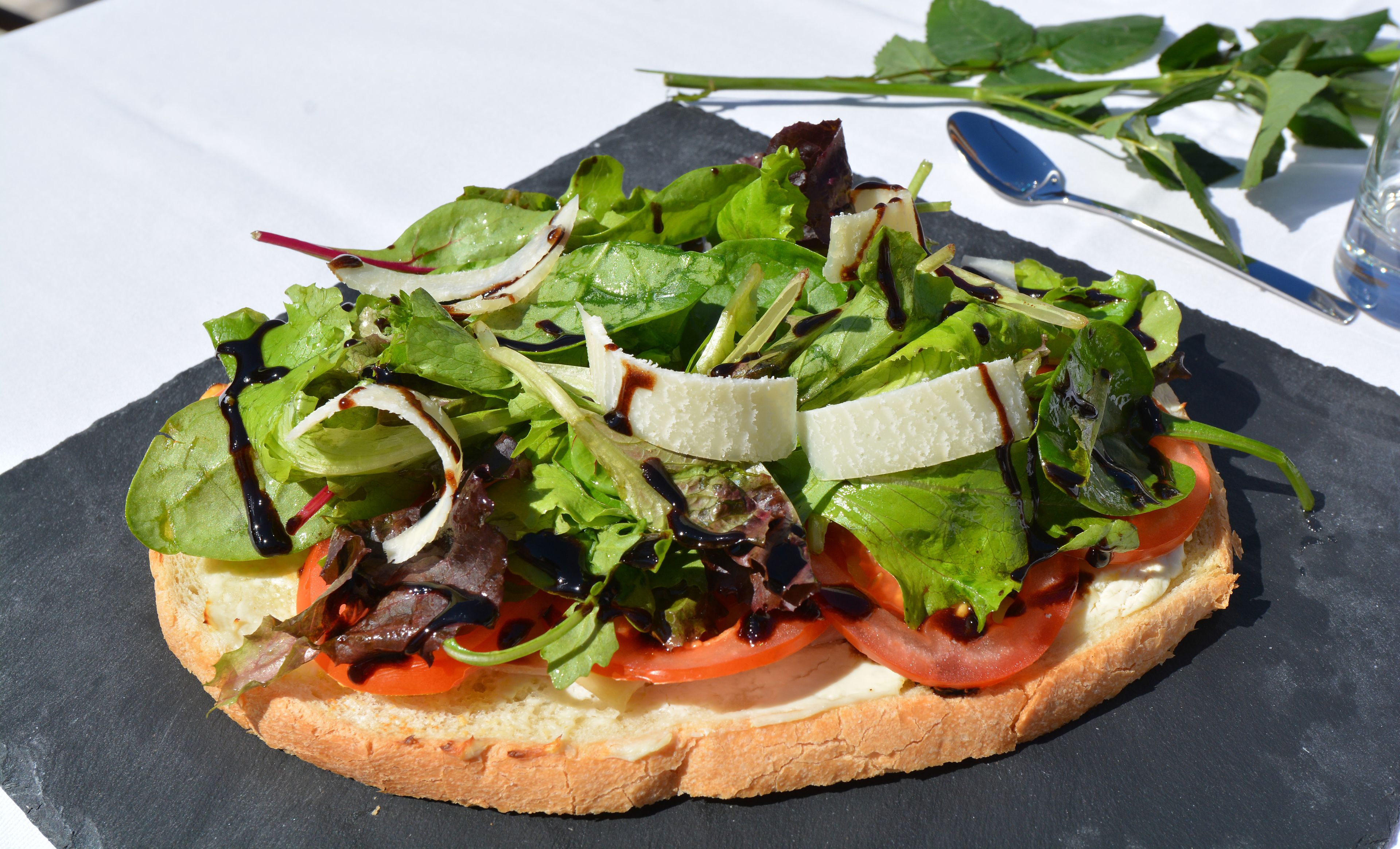 A sandwich with various greens and cheese on a slice of bread.