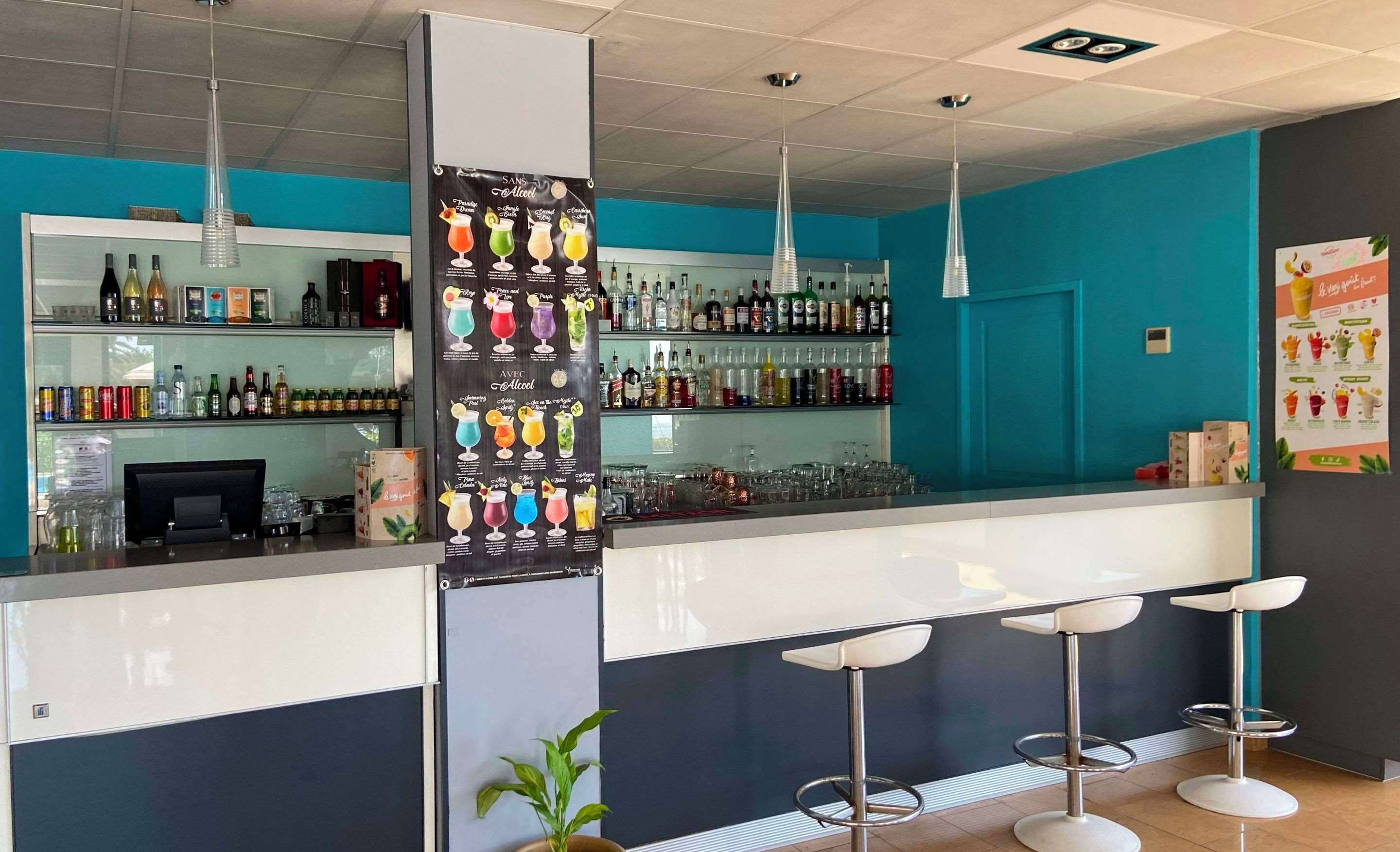 A bar area with a counter, stools, and a variety of bottles and glasses.
